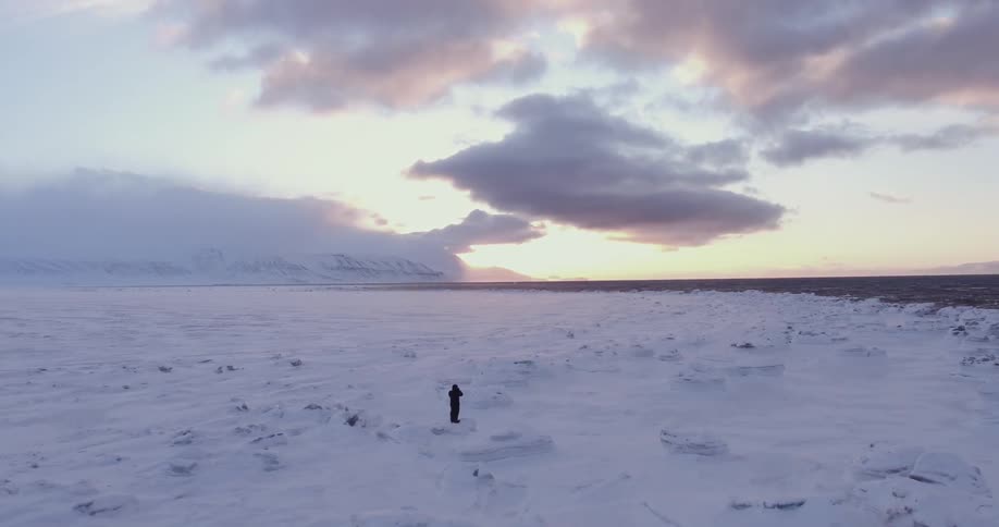 A man stands in a snowy icy field
