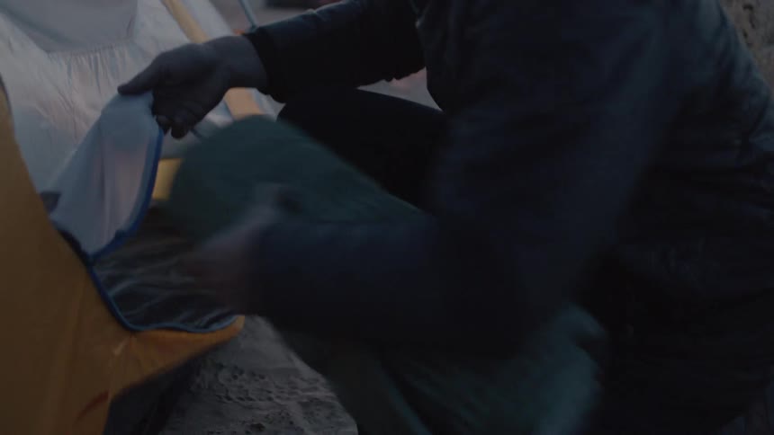 A person unzipping a tent