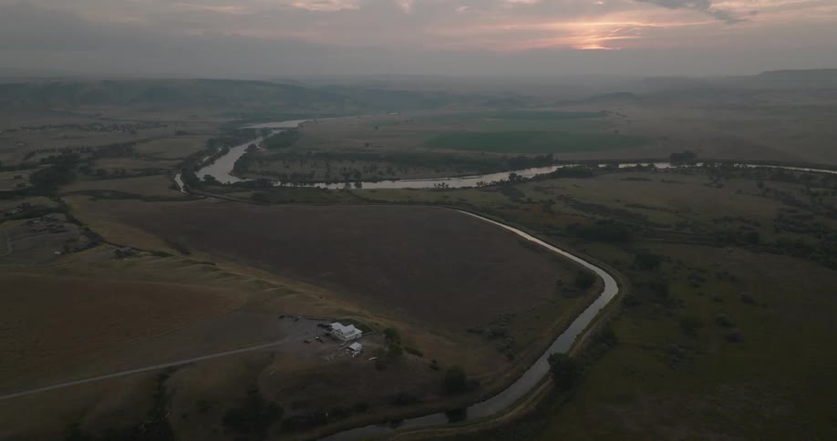 Aerial view of a rural landscape at sunset with winding river and distant hills