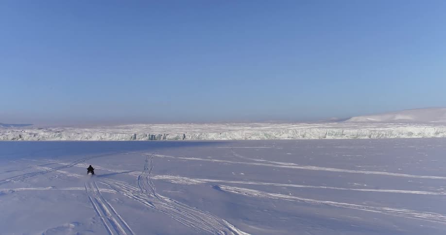 A person rides a snowmobile in the wilderness on a clear day