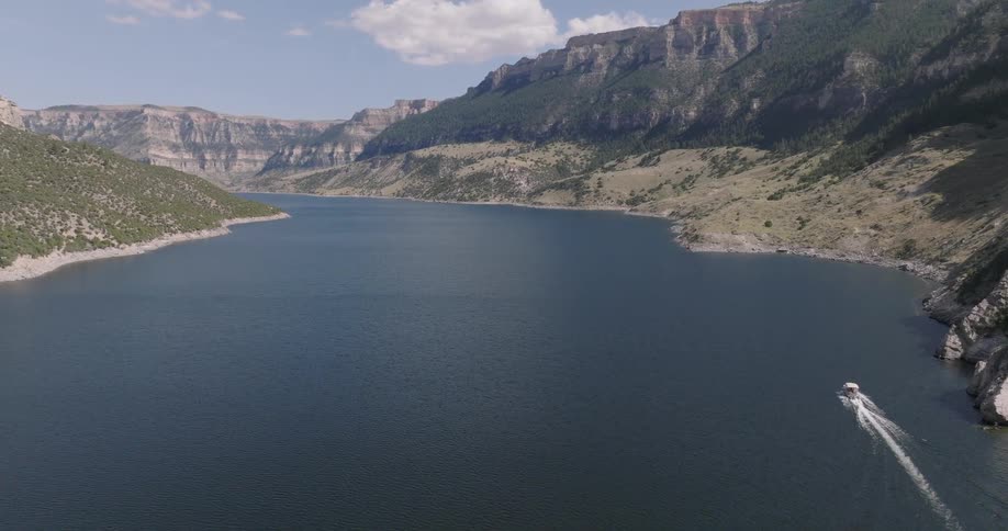 Sea canal with a speeding boat surrounded by mountains
