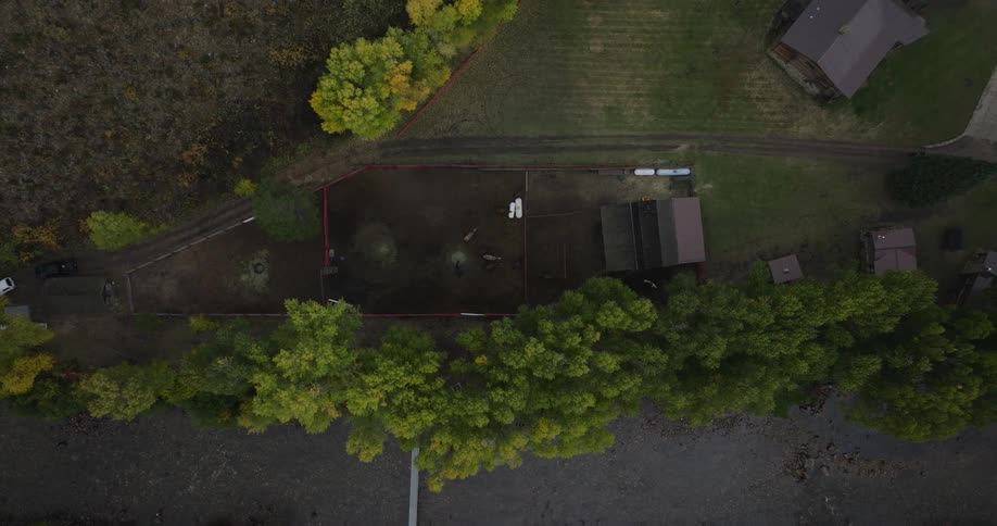 Aerial view of rural houses surrounded by trees and open land near a shoreline