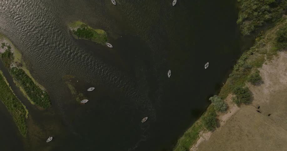 Aerial view of small boats on a river surrounded by green areas of vegetation