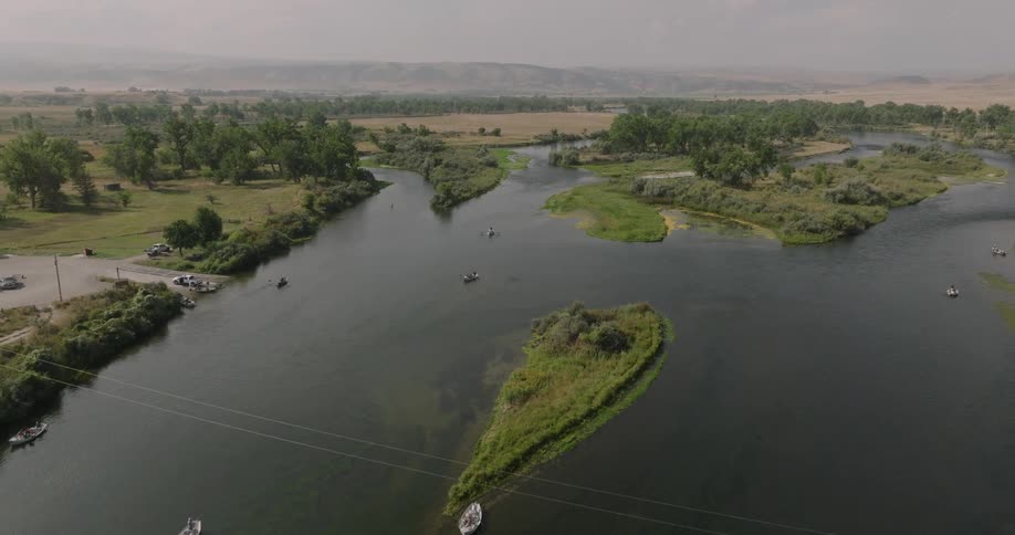 A lake filled with boats surrounded by green vegetation at midday
