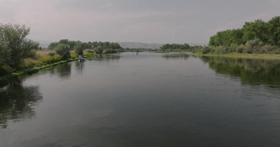 Calm river surrounded by vegetation and canoes in the background