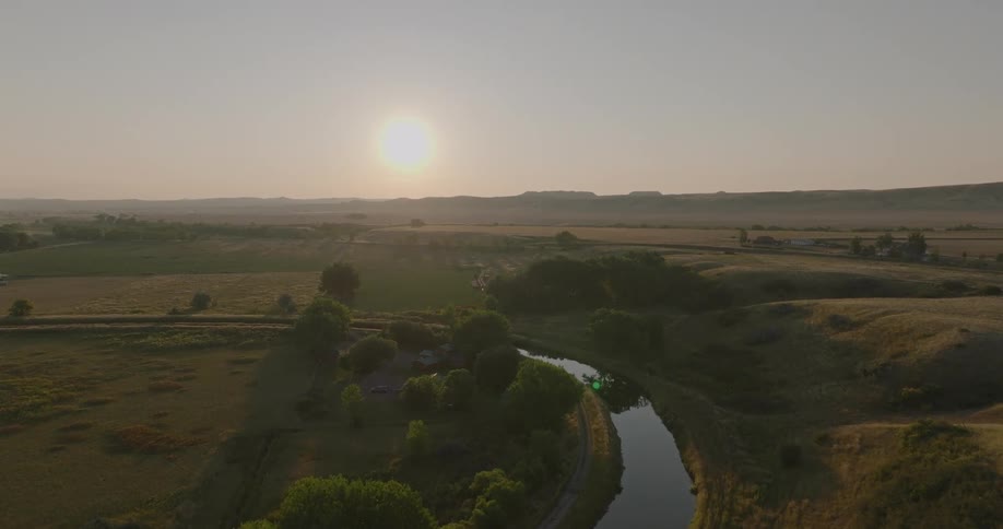 Aerial view of a large grassland with scattered trees and a small stream in the middle