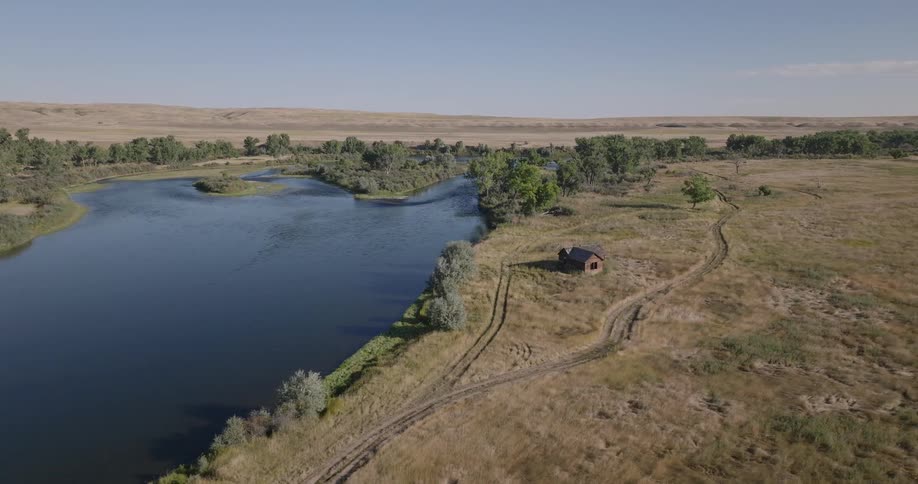 A cabin is by the lake on a long field