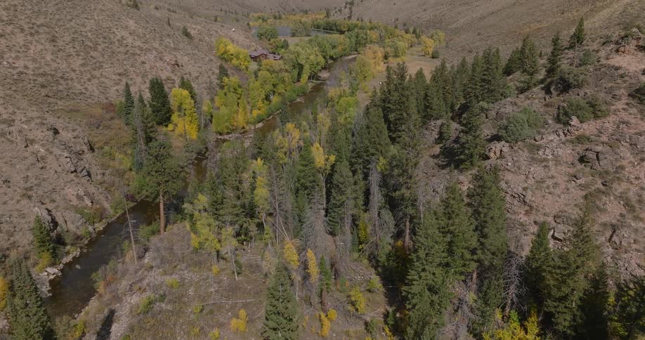 A river winds through a forested valley surrounded by dry rocky hills