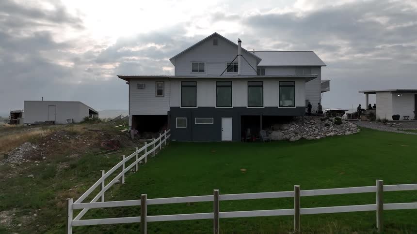 Isolated farmhouse sits under a cloudy sky on a grassy rural property