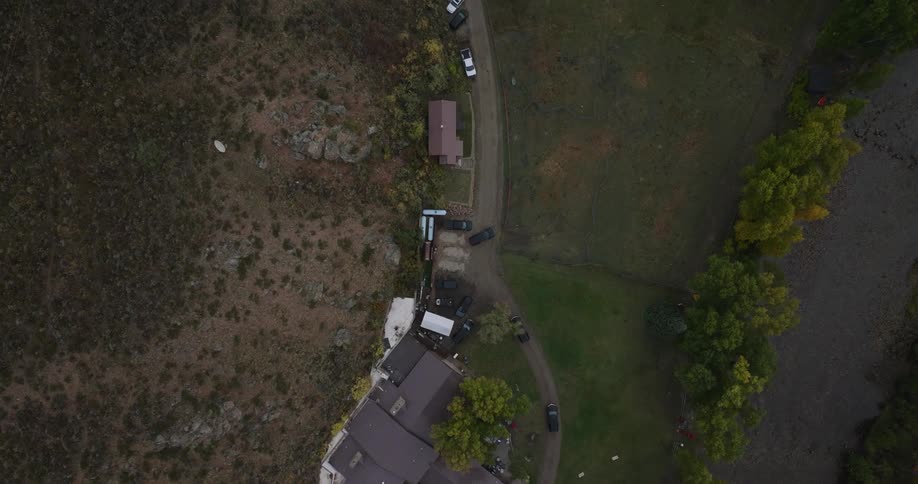 Aerial view of cars parked near rural houses and trees
