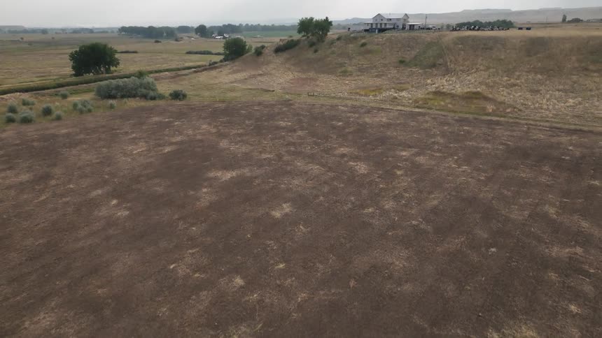Aerial shot of a natural area with a house on the horizon