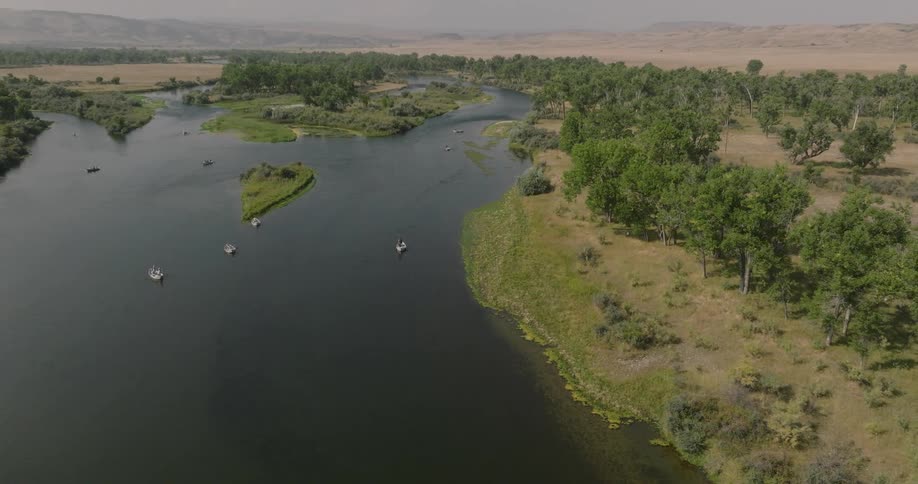 Aerial shot of a river with boats in a wooded area