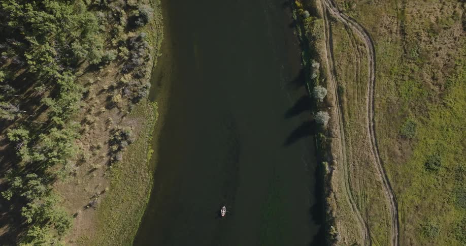 Aerial view of a river winding through grassy terrain with a small boat in the water