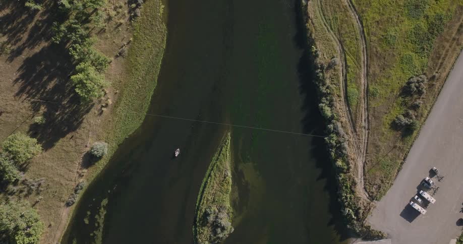 Boats navigate the river near a small island located close to a boat ramp