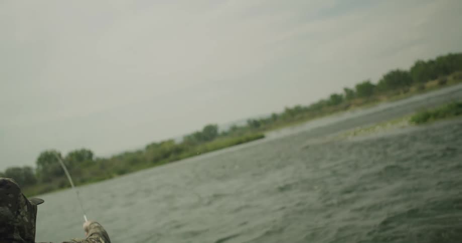 The man is smoking a cigar while he fly fishes