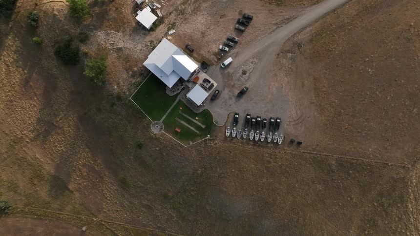 Aerial view of a rural property with buildings vehicles and boats arranged on dry land