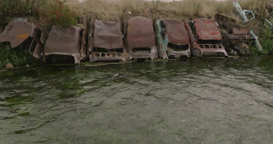 Rusted vehicles with their carcasses stuck in a river
