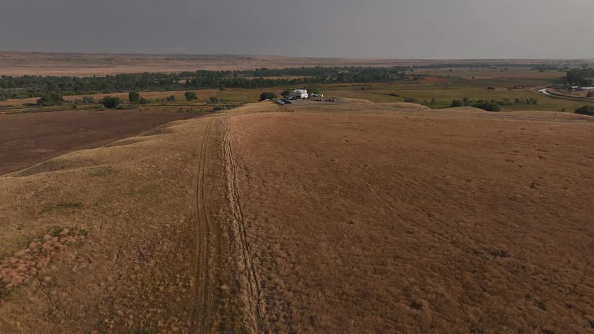 Aerial shot of an arid landscape with forest and mountains in the background