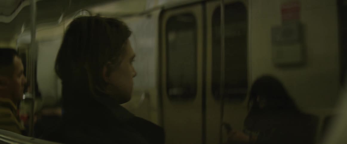 A man is sitting as he rides in a subway car