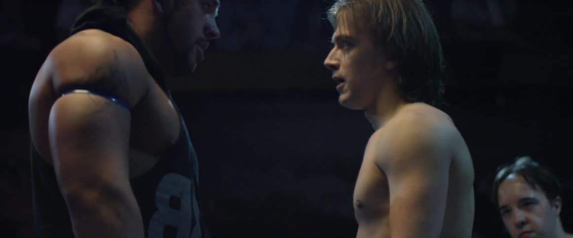 Two wrestlers face off in a dark ring