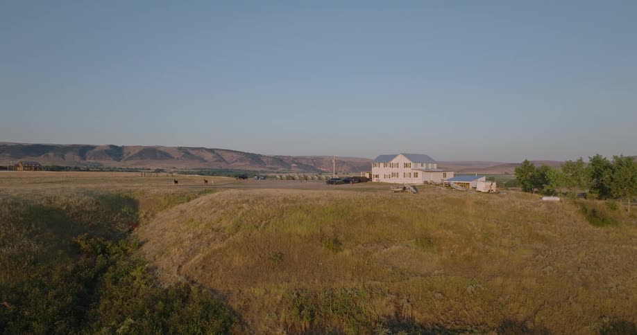 Rural house in a flat environment surrounded by mountains against a clear blue sky without clouds