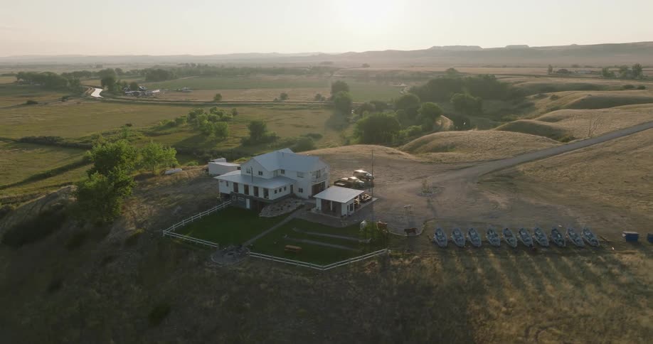 A rural house with boats sits on dry land at sunset