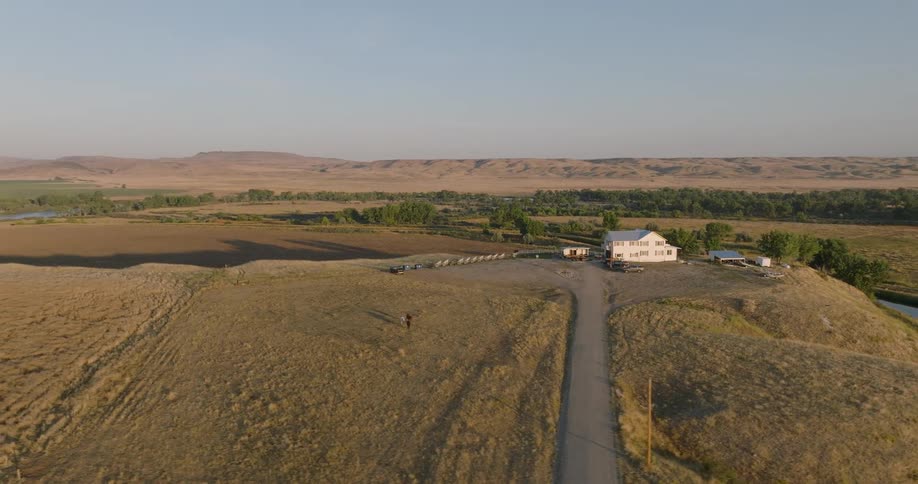 A building on a highland is surrounded by grassland at midday
