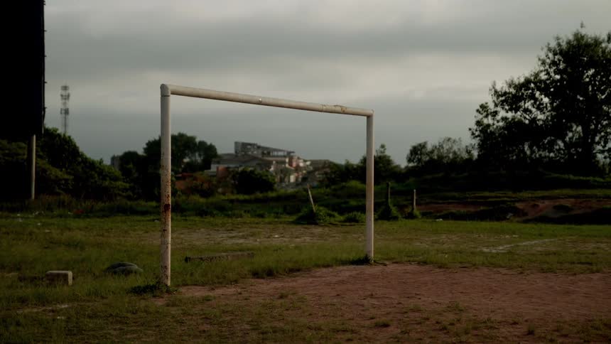 A goal post outdoors on an unkempt soccer field during daytime