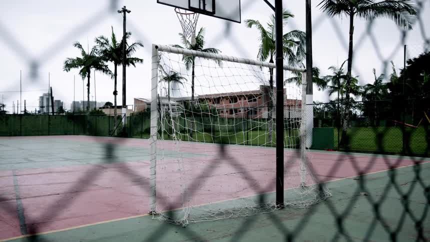 A basketball court outdoors with palm trees around the court