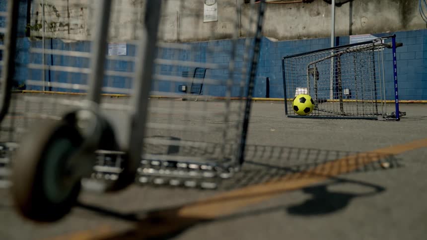 A soccer ball is in the shopping cart by the building