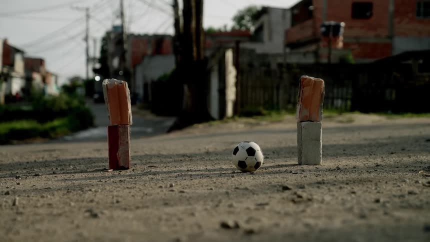Soccer ball between brick goalposts on a dirt street