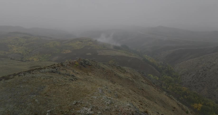 Fog covers a rugged mountain landscape under overcast skies