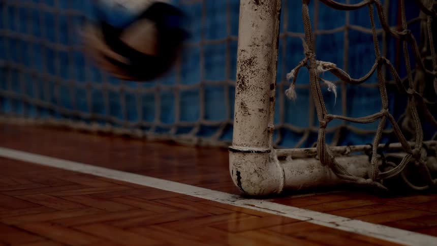 Close up of a netted goalpost in an indoor play area as a ball is played into it