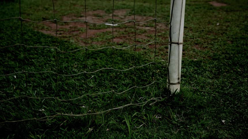 Close up of the bottom corner of a goal post and net on a soccer field during daytime