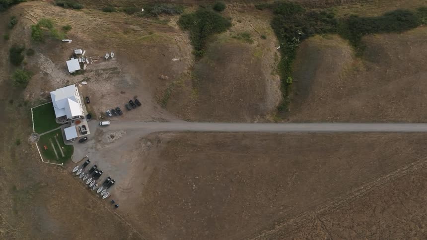 Rural property with boats and vehicles on dry open land seen from above