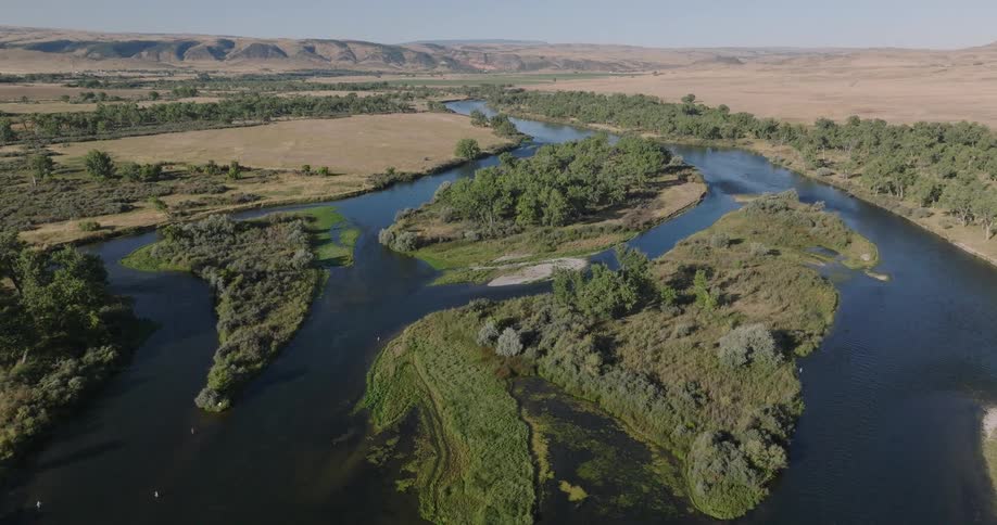 Aerial view of a winding river through grasslands and trees
