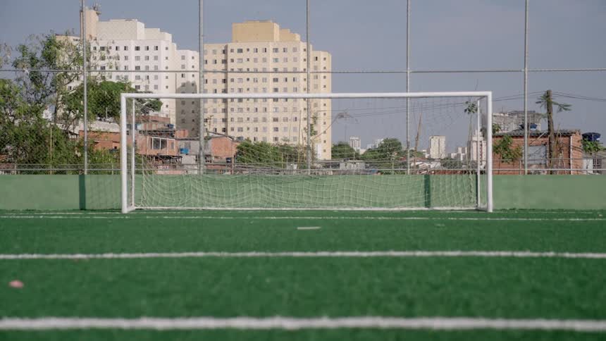 Soccer goal and the nearby fence allow views of apartment buildings in the background