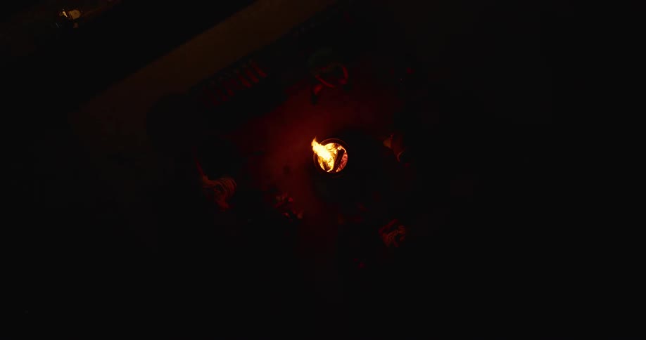 Friends sit around a campfire at night