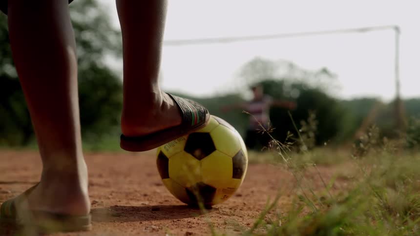 Two men are getting ready to play soccer on a dirt field