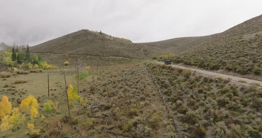 The vehicle is driving on the dirt road on the hill