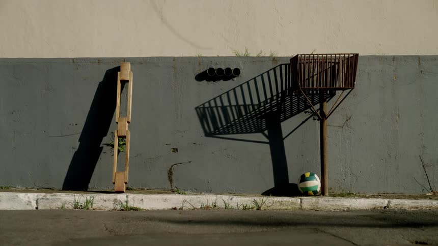 Volleyball leaning against an outdoor wall next to a trash can