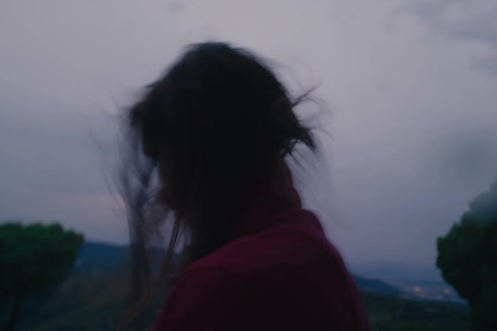 A woman looks down on the windy mountain peak