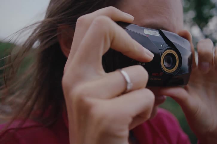 Woman outdoors taking pictures with a retro camera