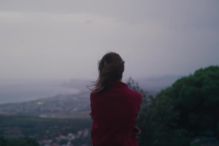 Woman in a red coat outdoors with her hair flying in the wind
