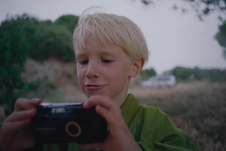 The boy is taking a photo outside on a windy day