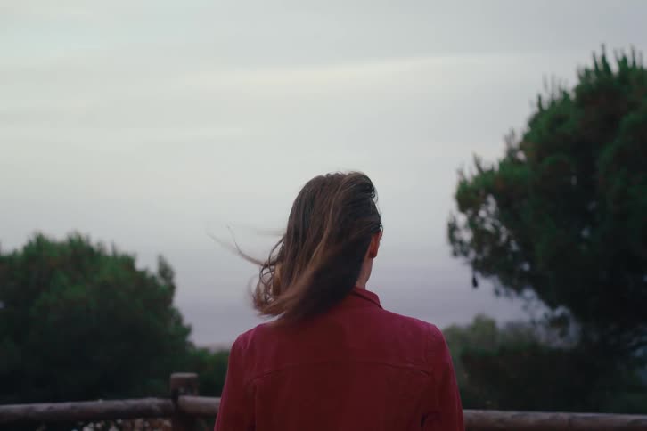 Woman takes photo with camera facing trees and sky