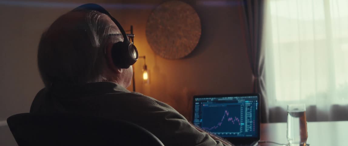 Older man analyzes stock chart on a laptop at home