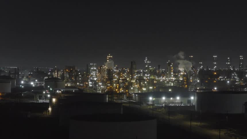 Smoke rises from the large factory at night
