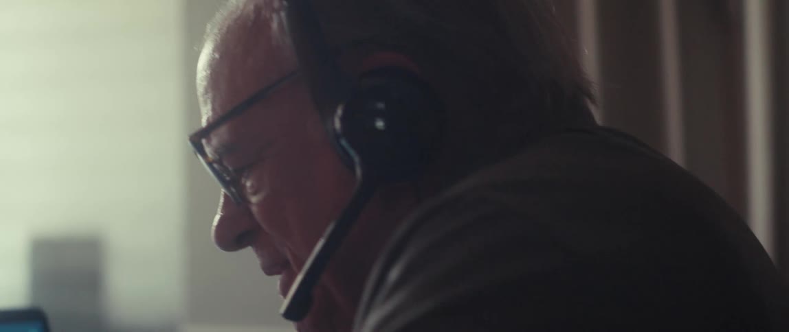 Elderly man with headphones sitting at a table