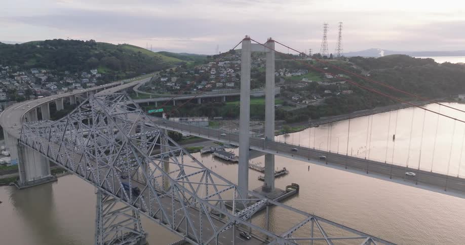 Aerial shot of bridges over the sea with vehicle traffic and an urban city in the mountains in the background